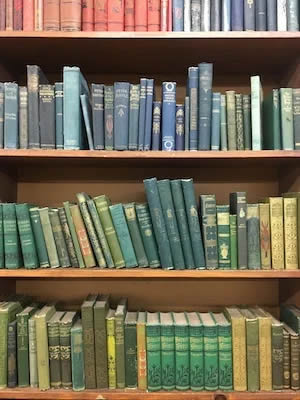 A stack of five books, including Moby Dick, A Certain World, and The Book of Wine, on a shelf.